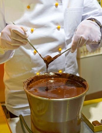 Um die Aromen bei der Herstellung zu entwickeln und ausgewogen zu verteilen, wird die Schokolade conchiert. Das bedeutet nichts anderes, als dass die Masse unter stetiger Bewegung erhitzt wird.