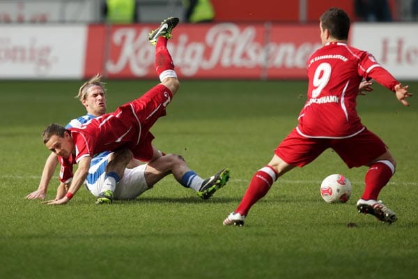 MSV-Kicker Sören Brandy (li). und Kaiserslauterns Chris Löwe ligen am Boden, Alexander Baumjohann bekommt die Kugel.