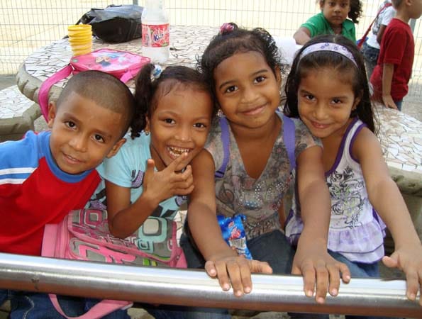 Gute Laune: Lachende Kinder stehen in Panama-Stadt am Straßenrand und winken den Vorbeifahrenden zu.