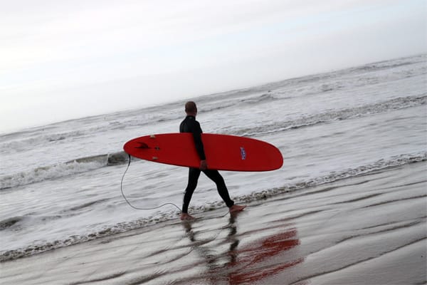 Surfer am Strand der Gower Peninsula, Wales.