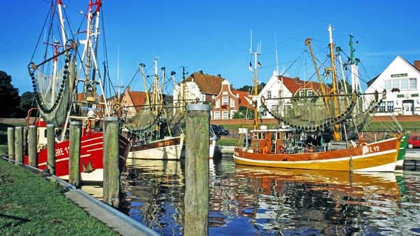 Die Fischerei ist immer noch die größte Einnahmequelle des beschaulichen Dorfes in der Krummhörn. Pro Tag und Boot fangen die Fischer rund 200 Kilo Nordseekrabben. Straßen sind nach Klaus Störtebeker benannt, Lokale heißen "Hafenkieker" oder "Fischers Fründ", es gibt ostfriesischen "Seebären"-Tee und "Nordseeschlamm"-Likör in den Souvenirgeschäften.