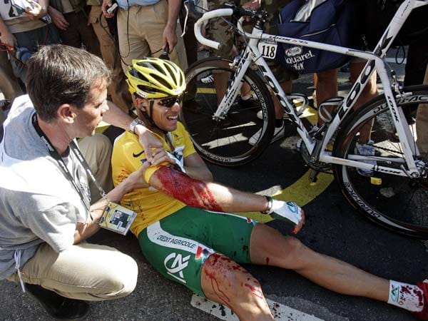 Nach der Zieldurchfahrt der ersten Etappe der Tour 2006 liegt der Norweger Thor Hushovd verletzt am Boden. Im Schlusssprint hat er sich an einem scharfen Gegenstand eines Fans am rechten Arm verletzt. Einen Tag zuvor gewann er im Prolog in Straßburg das Gelbe Trikot.