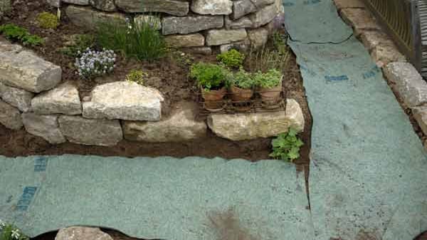 Vlies schützt vor Unkraut im Gartenweg.