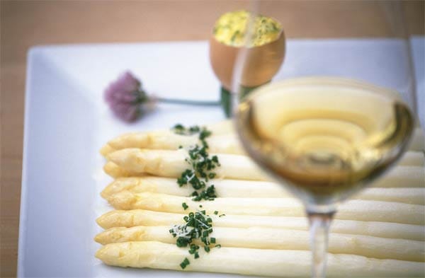 Stechfrischer Spargel wird in Südtirol mit Bozner Soße, Kartoffeln, Schinken und Parmesan serviert, dazu ein Glas trockener Weißwein.