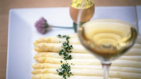 Stechfrischer Spargel wird in Südtirol mit Bozner Soße, Kartoffeln, Schinken und Parmesan serviert, dazu ein Glas trockener Weißwein.