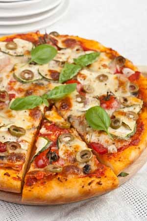 Zubereitung: Den Pizzaboden dünn ausrollen und mit den passierten Tomaten bestreichen. Mozzarella wahlweise in Scheiben schneiden und gleichmäßig auf dem Pizzaboden verteilen oder gleichmäßig drüberreiben. Das Gemüse bis auf die Oliven in Scheiben schneiden. Zucchini und die Champignons kurz in Olivenöl anbraten und zusammen mit den Strauchtomaten, den Artischocken und den Oliven auf der Pizza verteilen. Nach dem Backen mit Basilikumpesto und geriebenem Parmesan servieren.