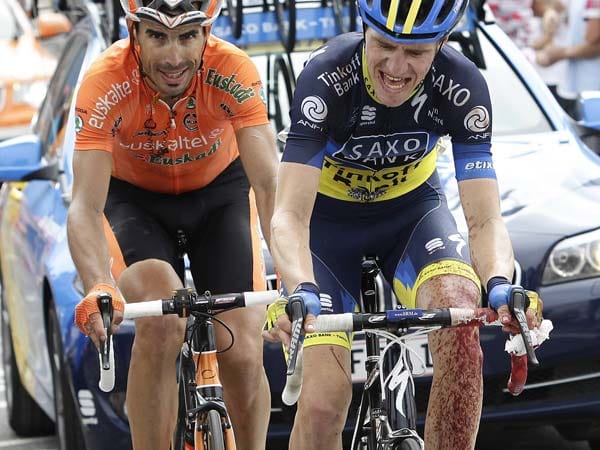 17. Etappe der Tour de France 2012: Der Däne Chris Anker Sörensen (re.) versucht ein Stück verhedderte Zeitung aus seinem vorderen Laufrad zu entfernen und verletzt sich dabei an den Fingern. Die Blutung kann erst nach Etappen-Ende gestoppt werden.