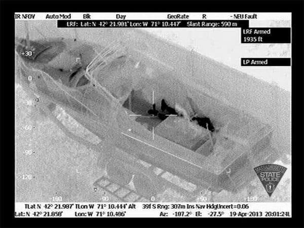 Wärmebildkameras in einem Polizeihubschrauber zeigen, wie der schwer verletzte 19-Jährige hinter einem Tisch liegt.