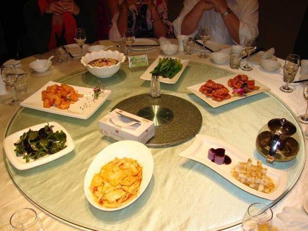 Gegessen wird traditionell an einem runden Tisch mit drehbarer Glasplatte – da heißt es schnell essen, bevor der Nachbar weiterdreht.