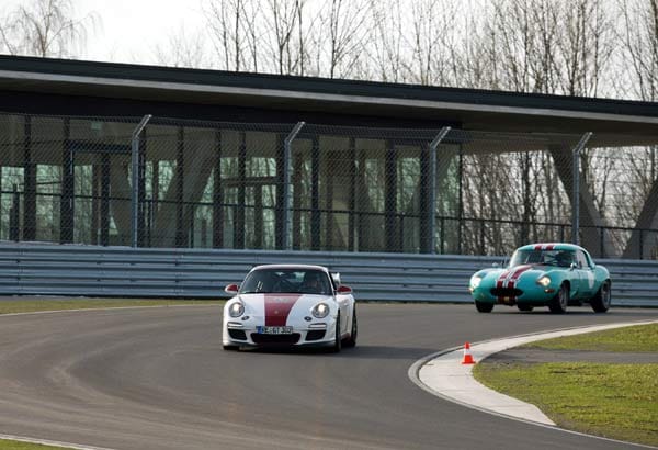 Vorbei am zweiten Clubhaus geht es in eine Schikane und danach auf die lange Gerade mit Höchstgeschwindigkeiten über 200 km/h. Im Hintergrund der Jaguar E-Type des Grafen und seines Gotcha Historic Racing Teams.