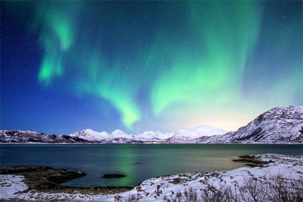 Polarlichter werden durch das Auftreffen geladener Teilchen, des so genannten Sonnenwindes, auf der Erdatmosphäre hervorgerufen. Generell gilt: Je näher am Nordpol, desto spektakulärer ist die Show der Polarlichter.
