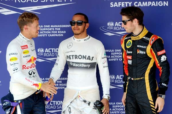 Ein Bild, das Bände spricht: Der schelmisch grinsenden Hamilton (Mi.) lässt sich von einem leicht angefressenen Vettel (li.) beglückwünschen.