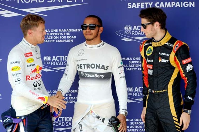 Ein Bild, das Bände spricht: Der schelmisch grinsenden Hamilton (Mi.) lässt sich von einem leicht angefressenen Vettel (li.) beglückwünschen.
