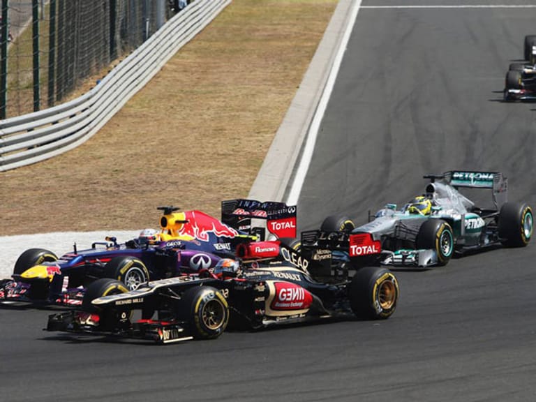 Beim Rennstart gerät Sebastian Vettel (li.) unter Druck. Romain Grosjean im Lotus (vorn) und Nico Rosberg greifen den Weltmeister an. Er kann seine Position aber behaupten.