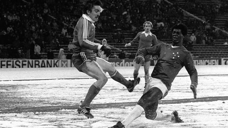 Der letzte Glanzpunkt der legendären Bayern der 1970er Jahre ist der Weltpokal 1976. Im Hinspiel im verschneiten Münchner Olympiastadion wird Cruzeiro Belo Horizonte mit 2:0 bezwungen. Dem Brasilianer im Bild scheint der weiße Untergrund nicht sonderlich zu gefallen.