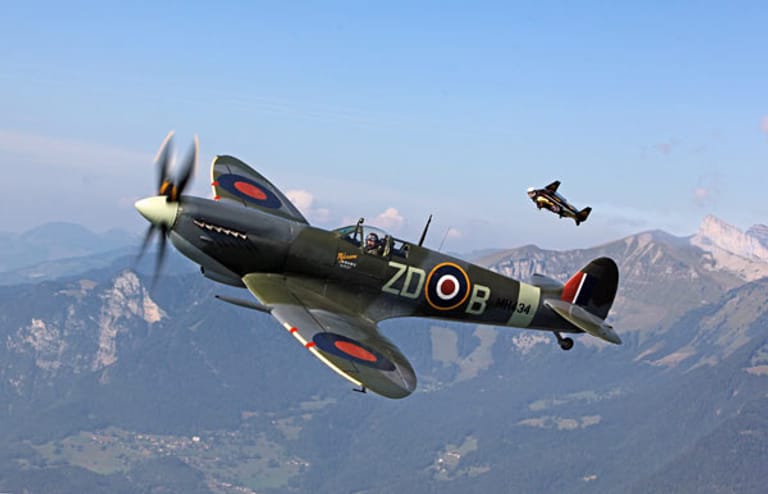 Die Spitfire ist einer der wertvollsten Oldtimer – berühmt wurde der Flieger bei der Luftschlacht um England. Im Hintergrund ein Springer im Wingsuit.