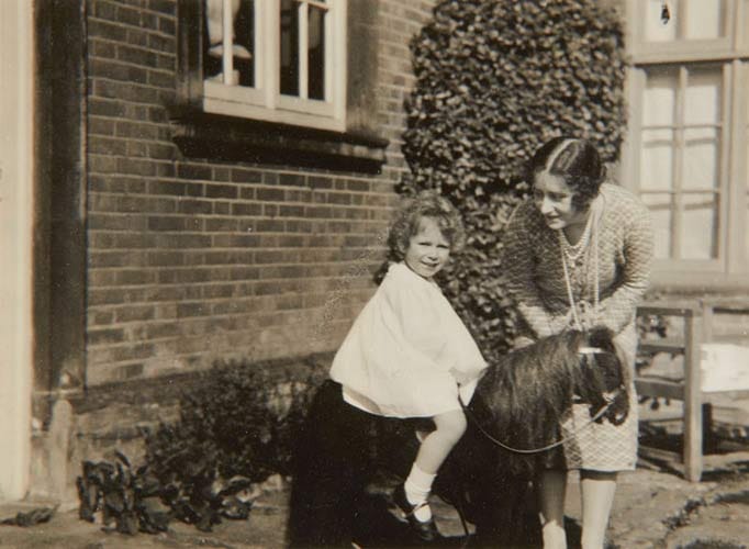 Schon im zarten Kindesalter hatte die heutige Queen ein Faible für Tiere. Hier reitet sie gerade auf einem Spielzeugpferd. Neben ihr ist ihre Mutter Elizabeth Bowes-Lyon zu sehen.