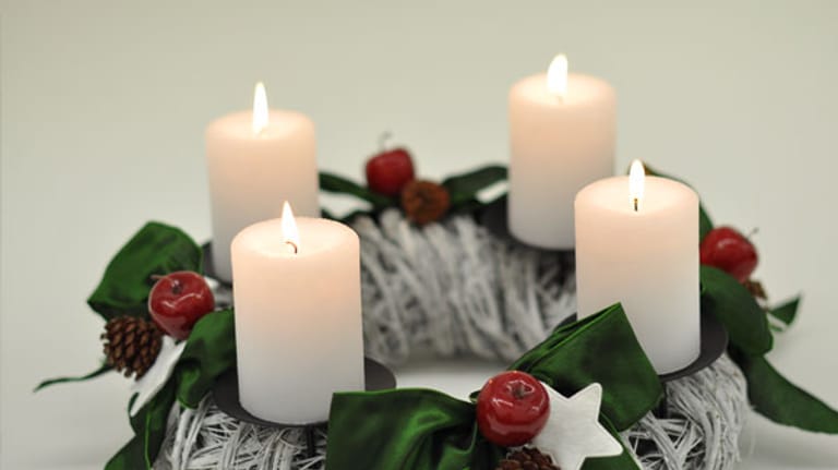 Moderne Adventkränze: weiße Kerzen auf Kranz aus gefärbten Weidenzweigen