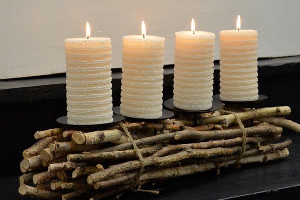 Moderne Adventkränze: Weiße Kerzen in Reihe auf einem Bündel aus Birkenzweigen