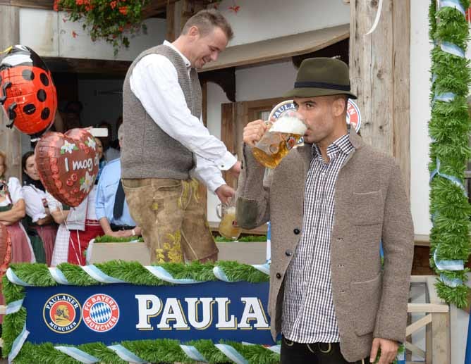 Pep Guardiola posiert mit einer Maß Bier. Der Bierpreis liegt dieses Jahr zwischen 9,40 Euro und 9,85 Euro.