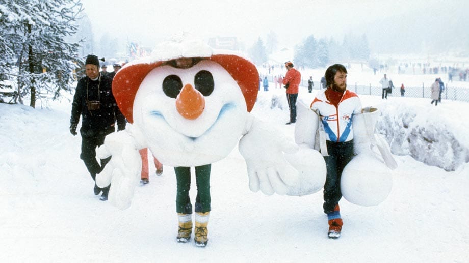 Olympia 1976 in Innsbruck: Maskottchen Schneemann macht eine Pause und lässt sich seine "Beine" tragen.