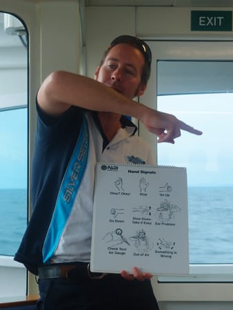 Tauchlehrer am Great Barrier Reef erklärt Handzeichen.