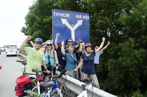 Radreise-Gruppe vor dem Schild Hanoi - Hoi-Chi-Minh-Stadt, Vietnam.