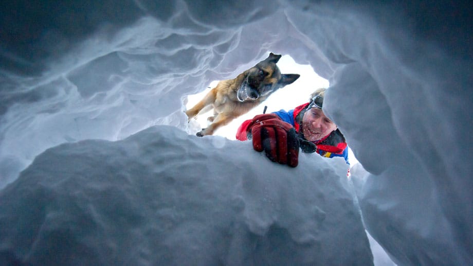Aus der Perspektive des Opfers: Bei einer Übung suchen ein Bergretter und sein Lawinenhund nach einem Verschütteten in einer Schneehöhle Aus der Perspektive des Opfers: Bei einer Übung suchen ein Bergretter und sein Lawinenhund nach einem Verschütteten in einer Schneehöhle