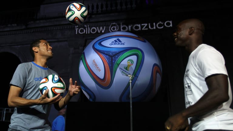 Bei der kommenden WM in Brasilien 2014 wird mit dem Brazuca gespielt. Der Brasilianer Hernanes (li.) und der Niederländer Clarence Seedorf probieren schon einmal die Flugeigenschaften aus.