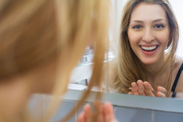 Spiegel: Spiegelbild von lachender Frau