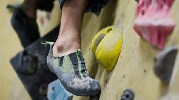 Jemand klettert eine Boulderwand hinauf. Nahaufnahme eines Kletterschuhs.