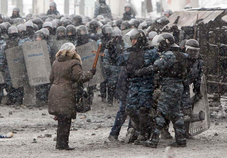 Eine Frau mit Kreuz redet auf Polizisten ein: Beschwichtigende Stimmen sind selten in diesen Tagen in Kiew.