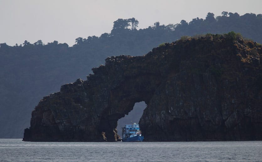 Myanmar: Ein Boot mit Tauchtouristen durchquert ein Felstor.