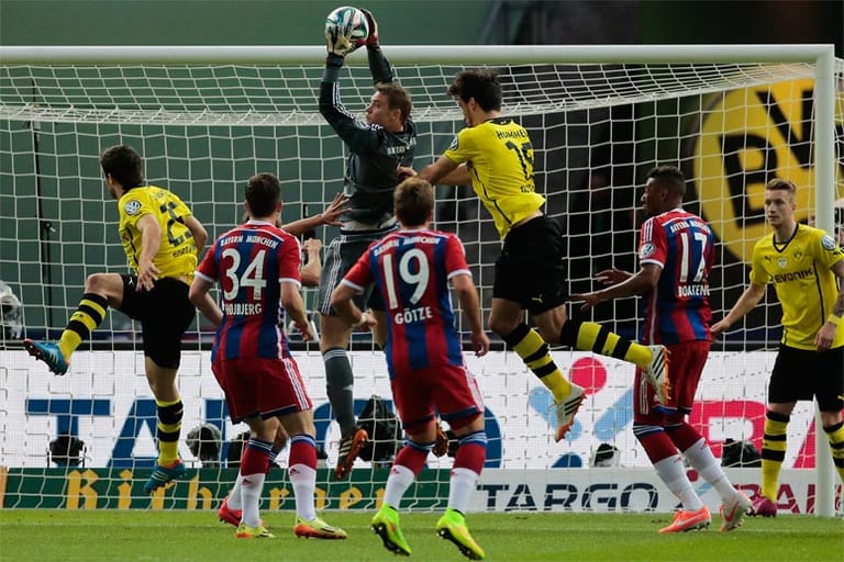 Nach einer Ecke der Borussia macht sich Bayern-Keeper Manuel Neuer ganz lang und fängt den Ball vor dem heraneilenden Dortmunder Innenverteidiger Mats Hummels ab.