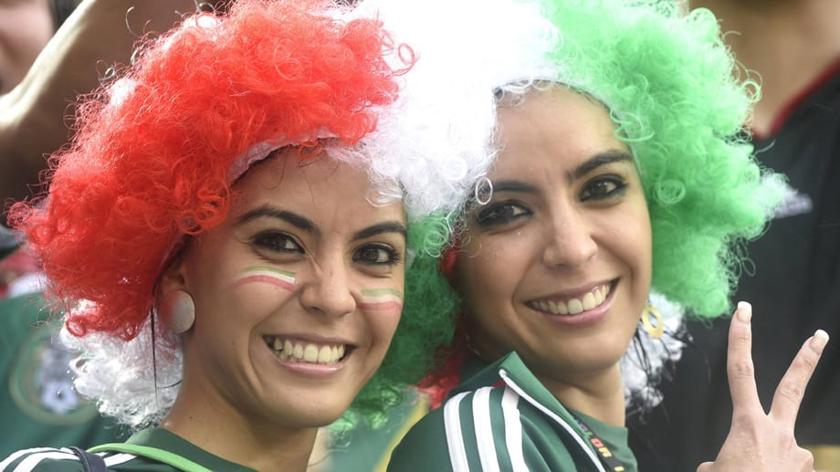 Wie Dante in grün-weiß-rot: Mexikanische Damen beim Daumen drücken mit Perücken.