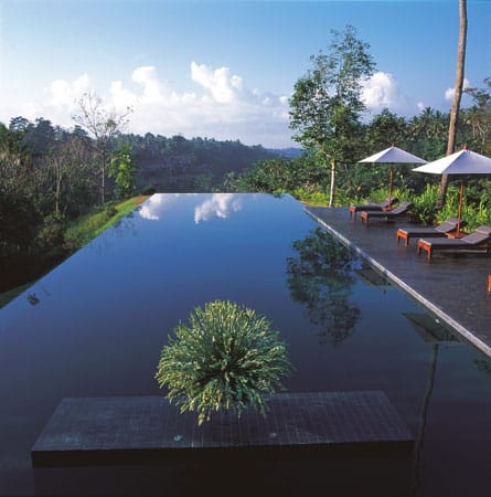 Der smaragdgrüne Pool auf der Terrasse des Alila Ubud Ressorts auf Bali scheint über dem Ayung Fluss zu schweben. Steinfließen umgeben das Sonnendeck, auf dem gemütliche Liegen mit balinesischen Sonnenschirmen garantieren, dass der Hotelgast absolut entspannen kann.