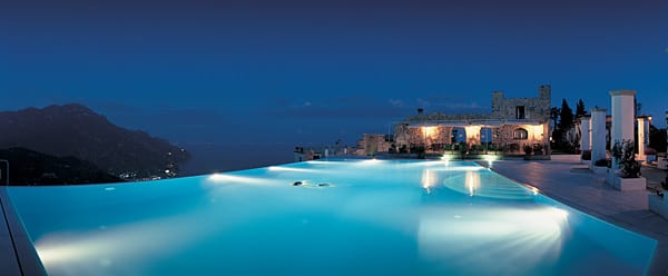 Gebaut auf dem höchsten Punkt Ravellos führt eine rosengesäumte Gasse zu dem elliptischen Infinity-Pool des Hotels Caruso in Italien. Der leicht erwärmte Pool scheint nahtlos in den Horizont überzugehen.