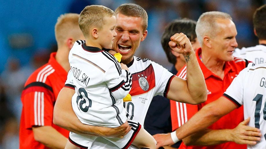 Die Familien kommen aufs Spielfeld und freuen sich mit den Spielern über den größten Triumph ihrer Karriere. Lukas Podolski nimmt seinen Filius auf den Arm und macht die Siegerfaust.