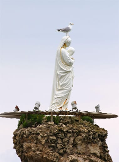 Hoch oben auf einem Felsen thront die weiße Statue der Heiligen Maria ein Stück weit im Meer. Sie gilt als die Beschützerin der Seeleute und bei der Wucht der Atlantikwellen, die sich donnernd an den schroffen Felsen brechen, hat sie einiges zu tun. Das hält Möwen nicht davon ab, es sich auf ihrem Kopf bequem zu machen.
