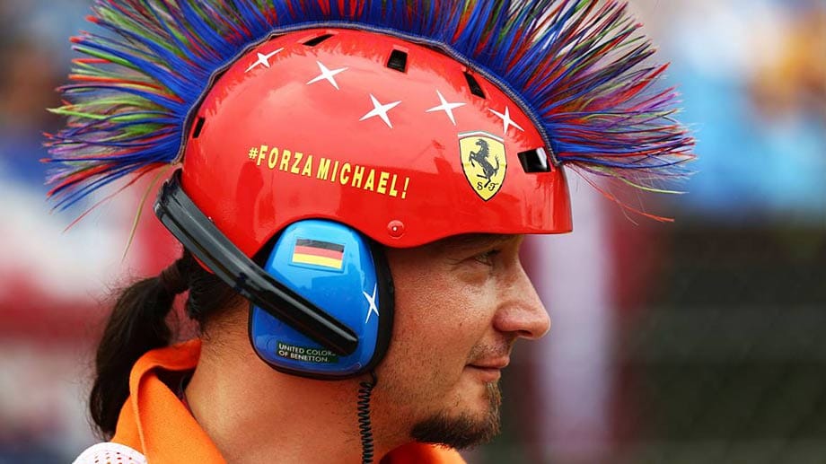 Die Streckenmarshalls erinnern beim Rennen mit ihren Kopfbedeckungen an Legenden der Formel 1. Hier wird an Rekordweltmeister Michael Schumacher gedacht.