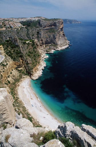 Die Cala Moraig bei Moraira an der Costa Blanca ist ein Kleinod: Rund um den Strand türmen sich bis zu 100 Meter hohe Felsen auf. Irgendwo dazwischen schwappt sanft das Mittelmeer an Land. Die Bucht wirkt wie gemalt: Seicht fällt der Strand ins glasklare Wasser ab.