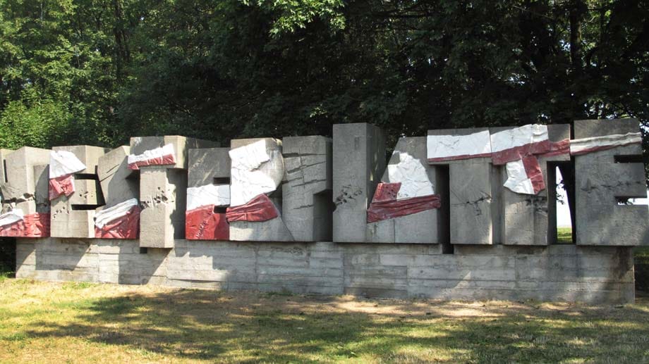 Neben gesprengten Bahngleisen findet sich der Schriftzug "Westerplatte", er wurde aus Trümmerteilen zusammengesetzt. Die zahlreichen Einschusslöcher sind auch nach 75 Jahren noch klar zu erkennen.