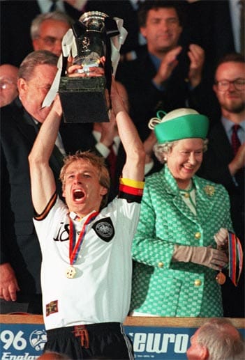 30.06.1996 im Londoner Wembley-Stadion: DFB-Kapitän Jürgen Klinsmann reckt unter den Augen der Queen den EM-Pokal in die Höhe. Zuvor hatte Sturmkollege Oliver Bierhoff das Finale gegen Tschechien mit einem Golden Goal entschieden. Nach der verkorksten WM 1998 gab Klinsmann nach 36 Spielen als Kapitän die Binde wieder ab.