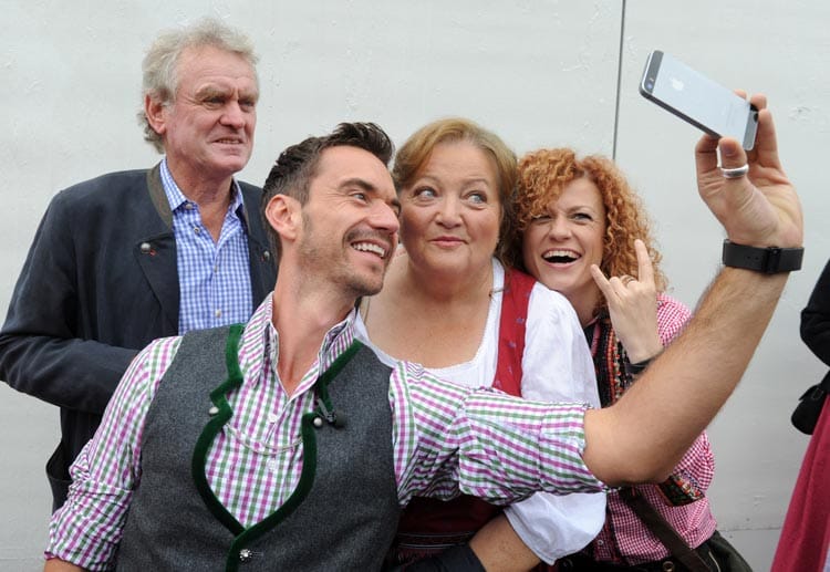 Der frühere Torhüter Sepp Maier (hinten, v. li. n. re.), Florian Silbereisen (vorne), die Schauspielerin Marianne Sägebrecht und Sängerin Lucy Diakovska stehen am Eröffnungstag des Oktoberfestes in München vor einem Festzelt zusammen und machen ein Selfie.