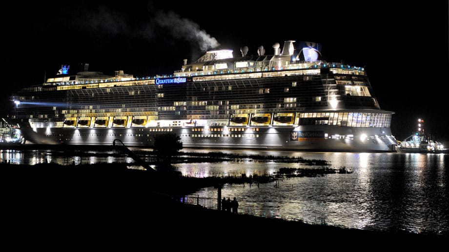 Nur als Schattenrisse zeichnen sich Zuschauer auf dem Emsdeich bei Weener (Niedersachsen) im Lichtschein des Kreuzfahrtschiff-Neubaus der Meyer-Werft "Quantum of the Seas" ab.