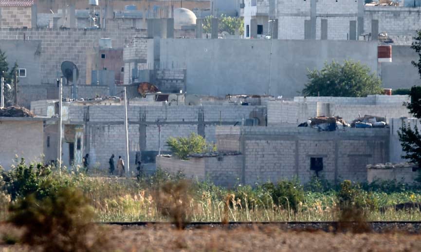 Kämpfer - vermutlich des IS - schleichen durch einen Außenbezirk von Kobane.