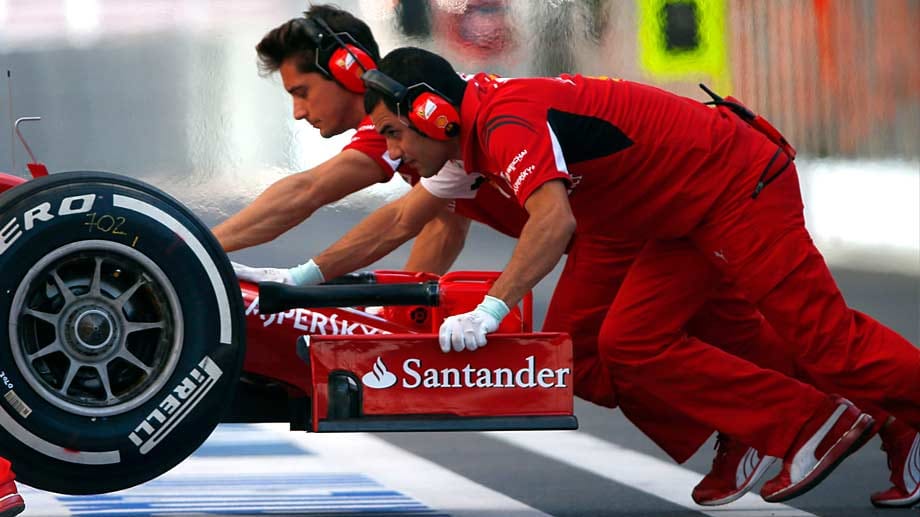 Alle Hände voll zu tun: Ferrari-Mechaniker schieben den Boliden von Kimi Raikkonen in die Box.