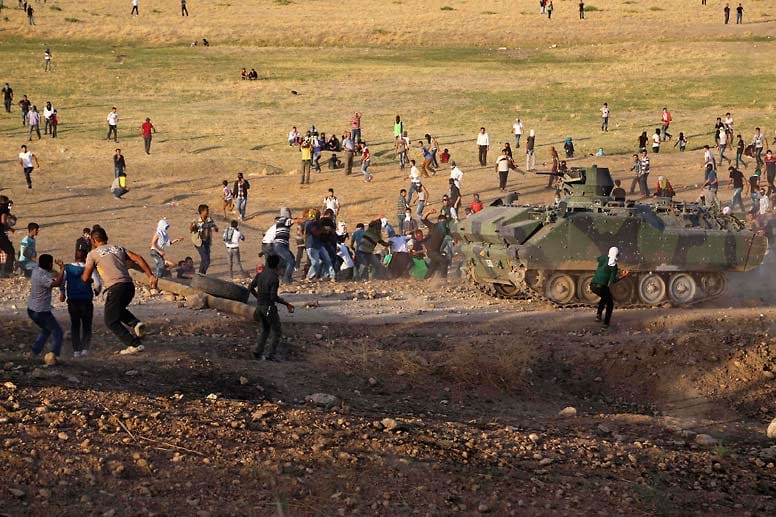 Auf der anderen Seite der Grenze im Südosten der Türkei attackieren Kurden türkische Panzer mit Steinen, weil diese nicht in den Konflikt eingreifen.