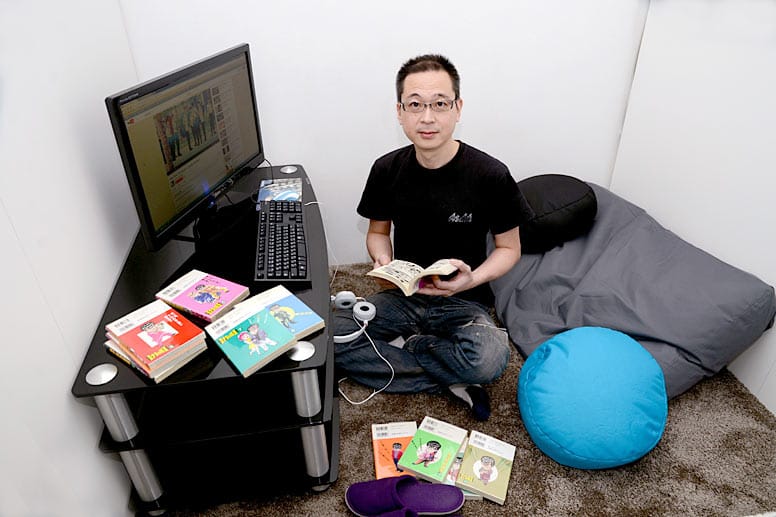 Der Besitzer des Manga-Cafès Tatsuhiro Mizutani sitzt mit einem Manga-Comic in einer kleinen Kabine in seinem Café.