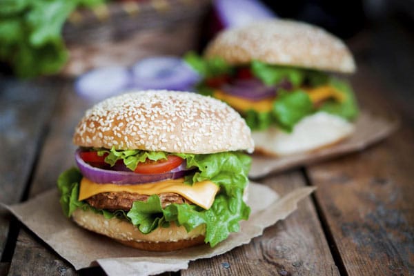 Wer es knackig mag, kann seinen Burger mit frischen Zutaten wie Eisbergsalat, Tomaten, Zwiebeln und gutem Cheddar-Käse verfeinern.
